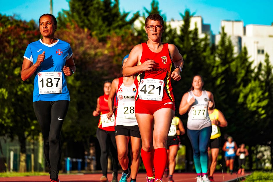 Runners in sportswear with numbers running with unrecognizable competitors while participating in track and field competition